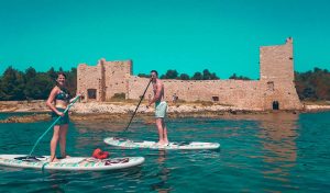 Two tourists standup paddleboarding around the Island of Vis in Croatia