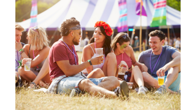 A group of friends enjoying a music festival on the beach, chatting and having a great time